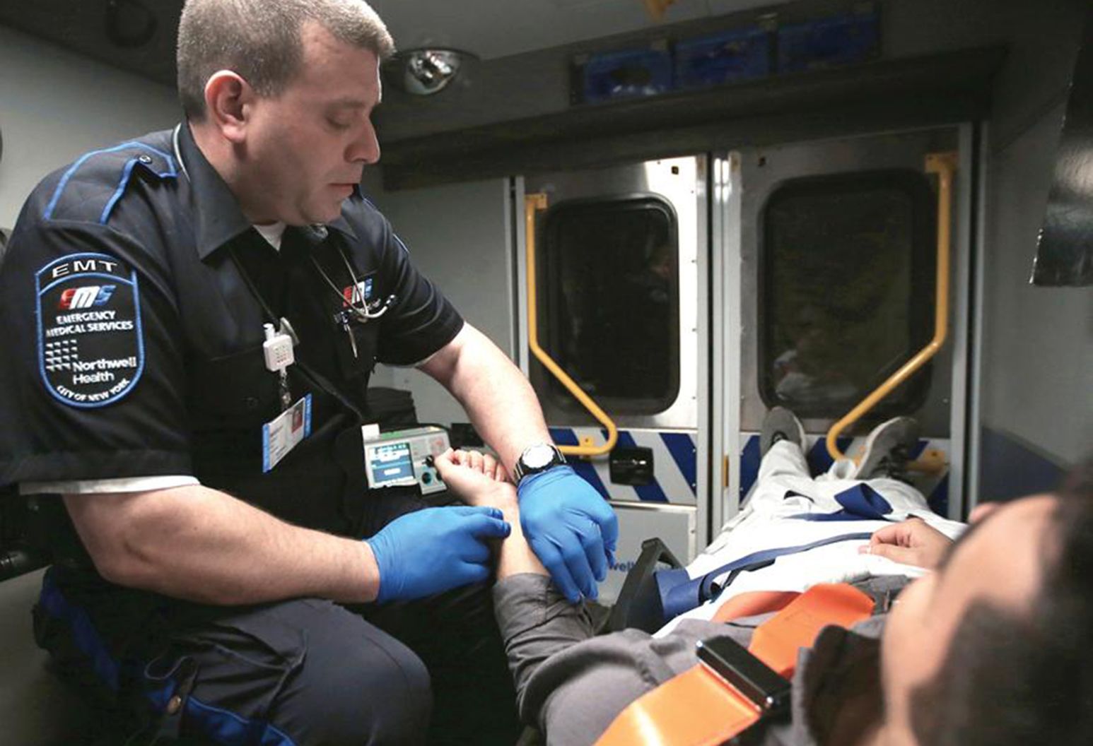 An EMT checks a patients pulse whilst in the back of an ambulance.